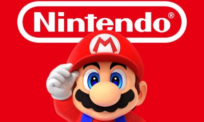 mario holding his hat while looking straight below white nintendo logo on red background